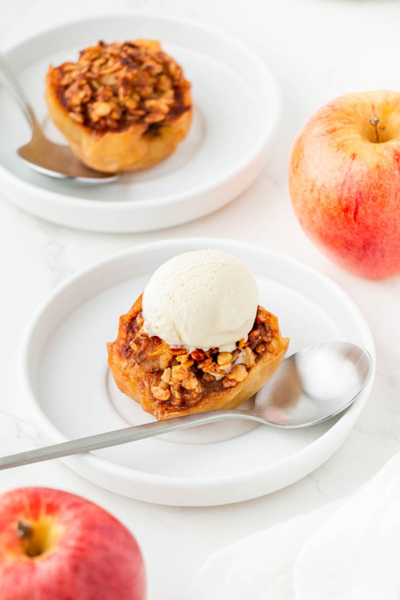 air fryer baked apples on white plates with vanilla ice cream and a spoon