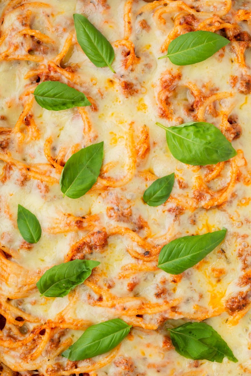 close up of air fryer baked spaghetti with fresh basil on top