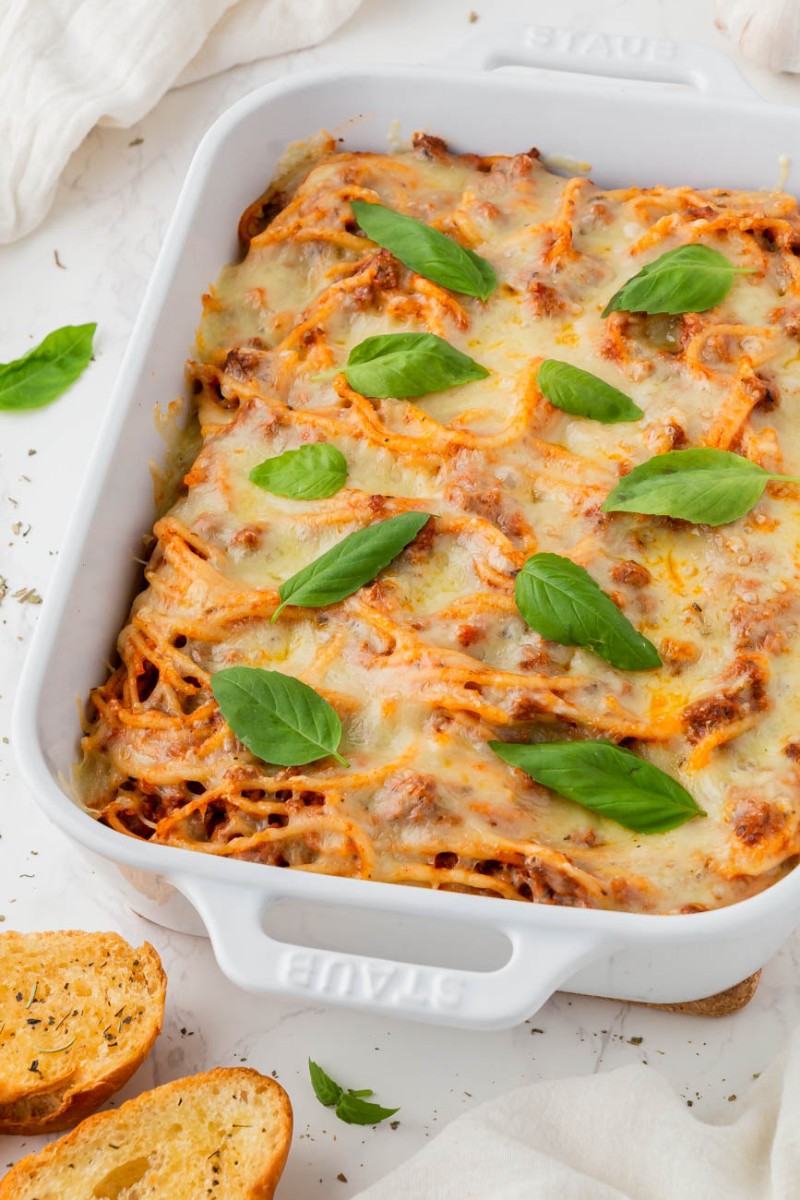 air fryer baked spaghetti in a white baking dish with basil on top