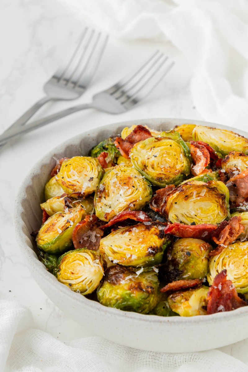 close up of air fryer brussels sprouts in a white bowl with bacon