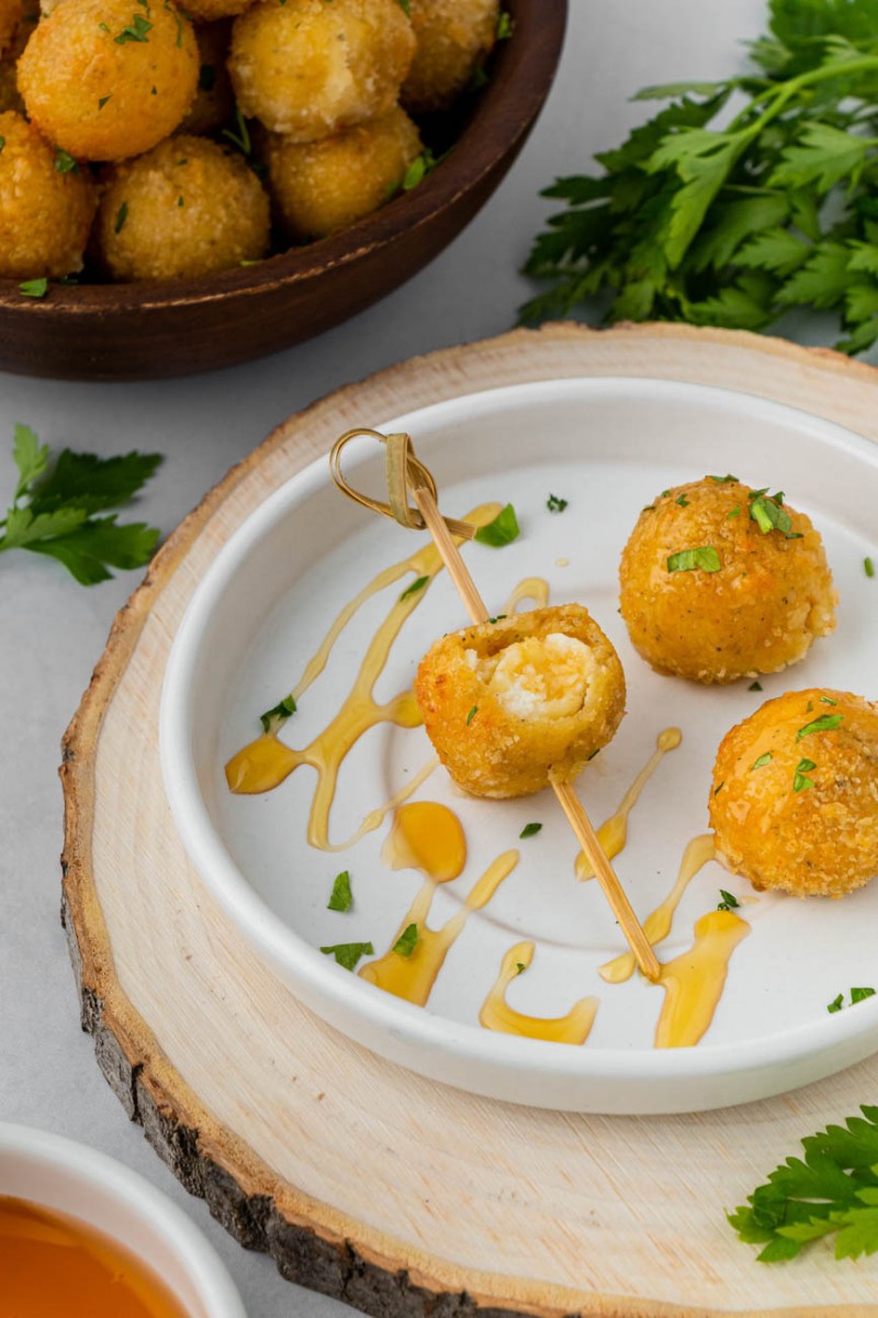 three goat cheese bites on a white plate, a bite taken from one of them