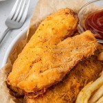 air fryer beer battered fish on a plate with french fries and ketchup