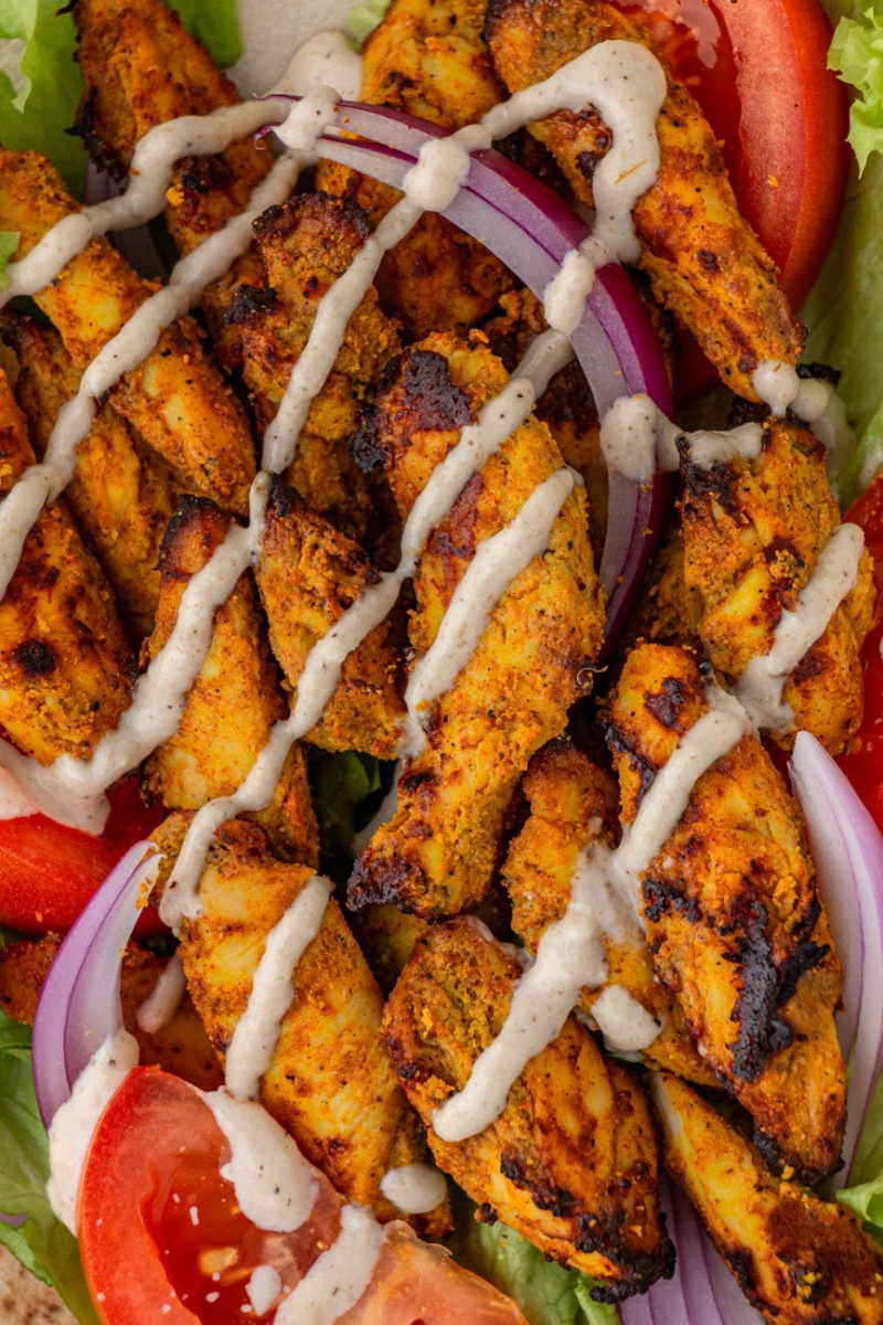 close up of air fryer chicken shawarma with tahini sauce drizzled on top