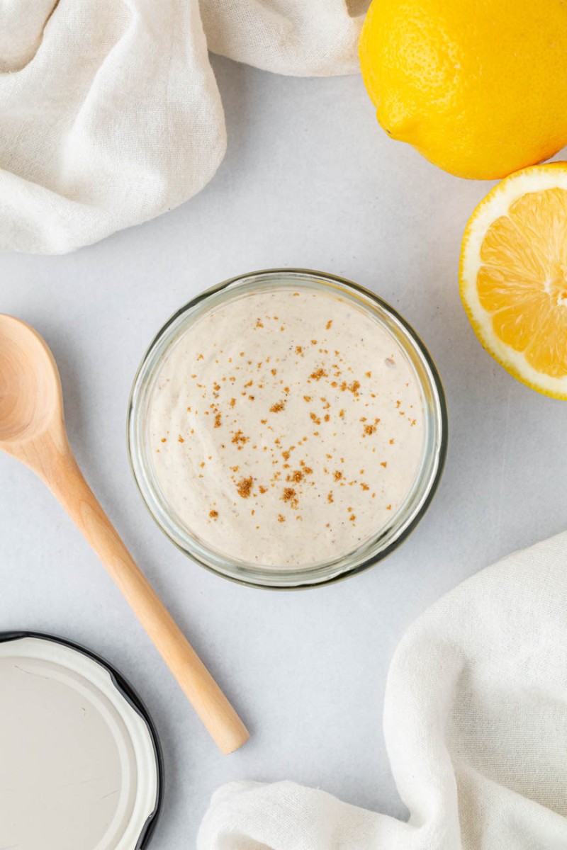 tahini sauce in a glass jar with lemons on the side