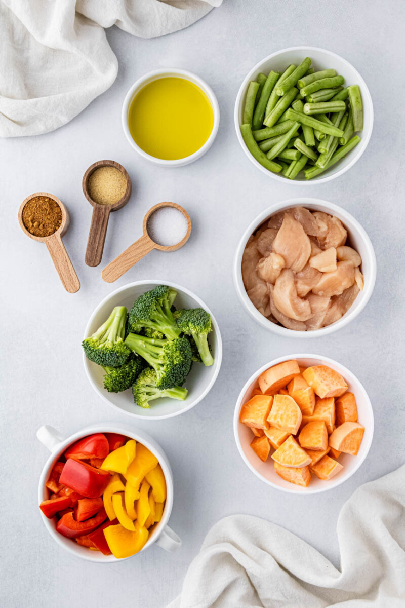 chicken, broccoli, bell peppers, olive oil, and spices in small ingredient bowls