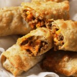 air fryer cheeseburger egg rolls on parchment paper and cut in half