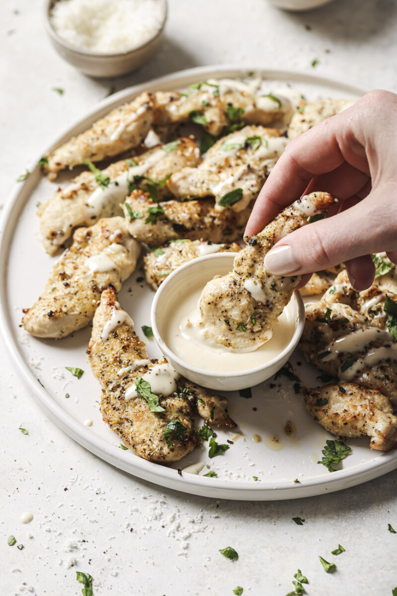 Air fryer ranch chicken being dipped into ranch dressing.