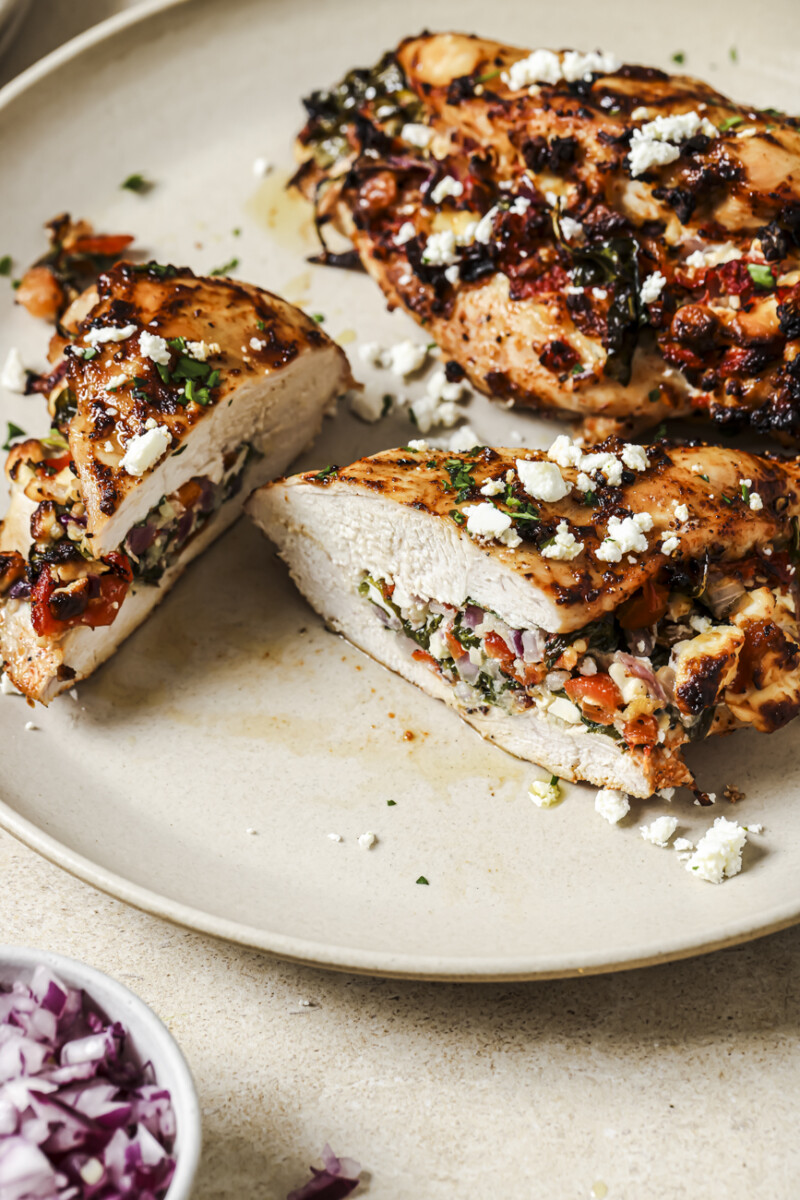 An air fryer stuffed chicken breast on a plate cut in half to show the filling.