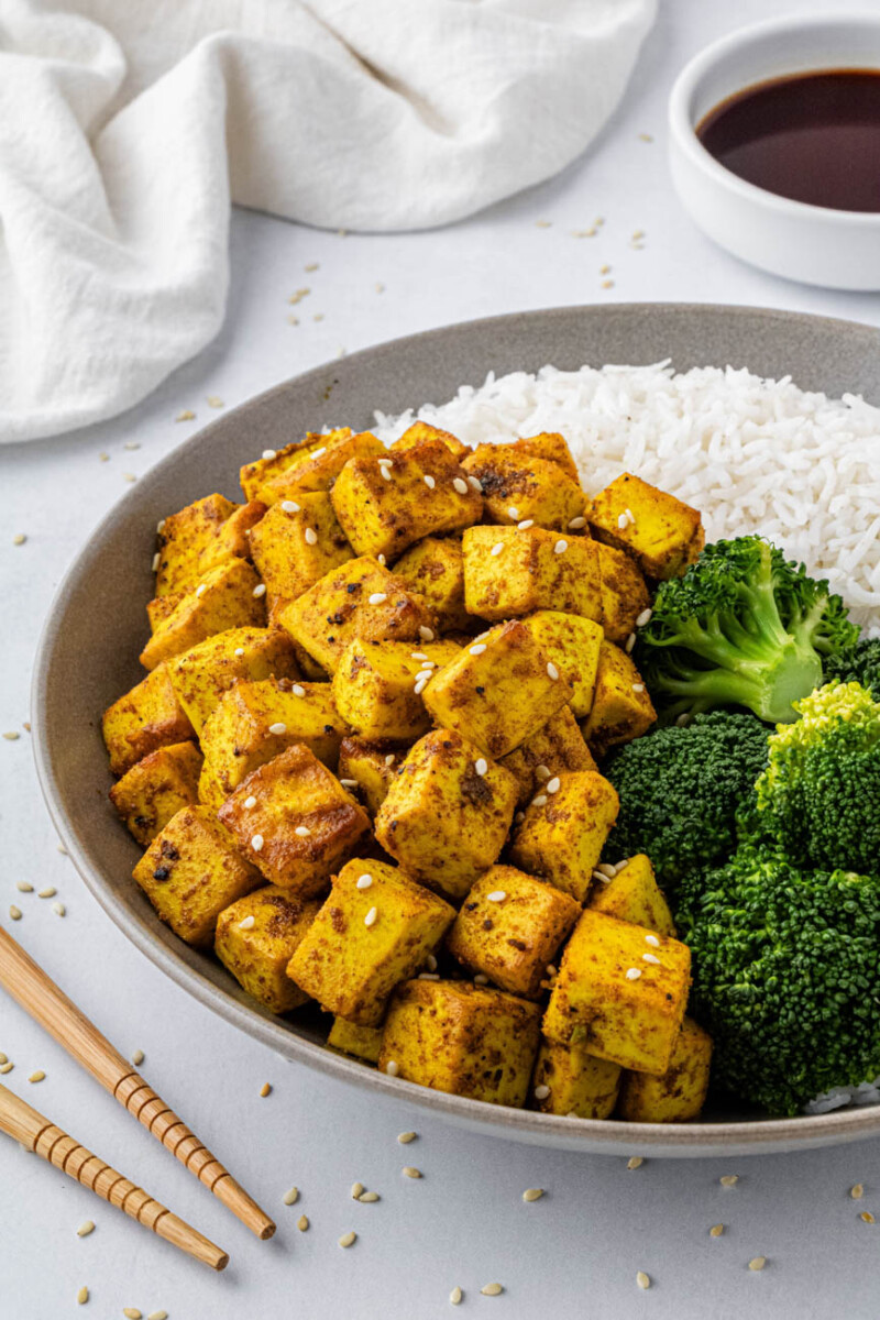 air fryer turmeric tofu on a white plate with white rice and broccoli