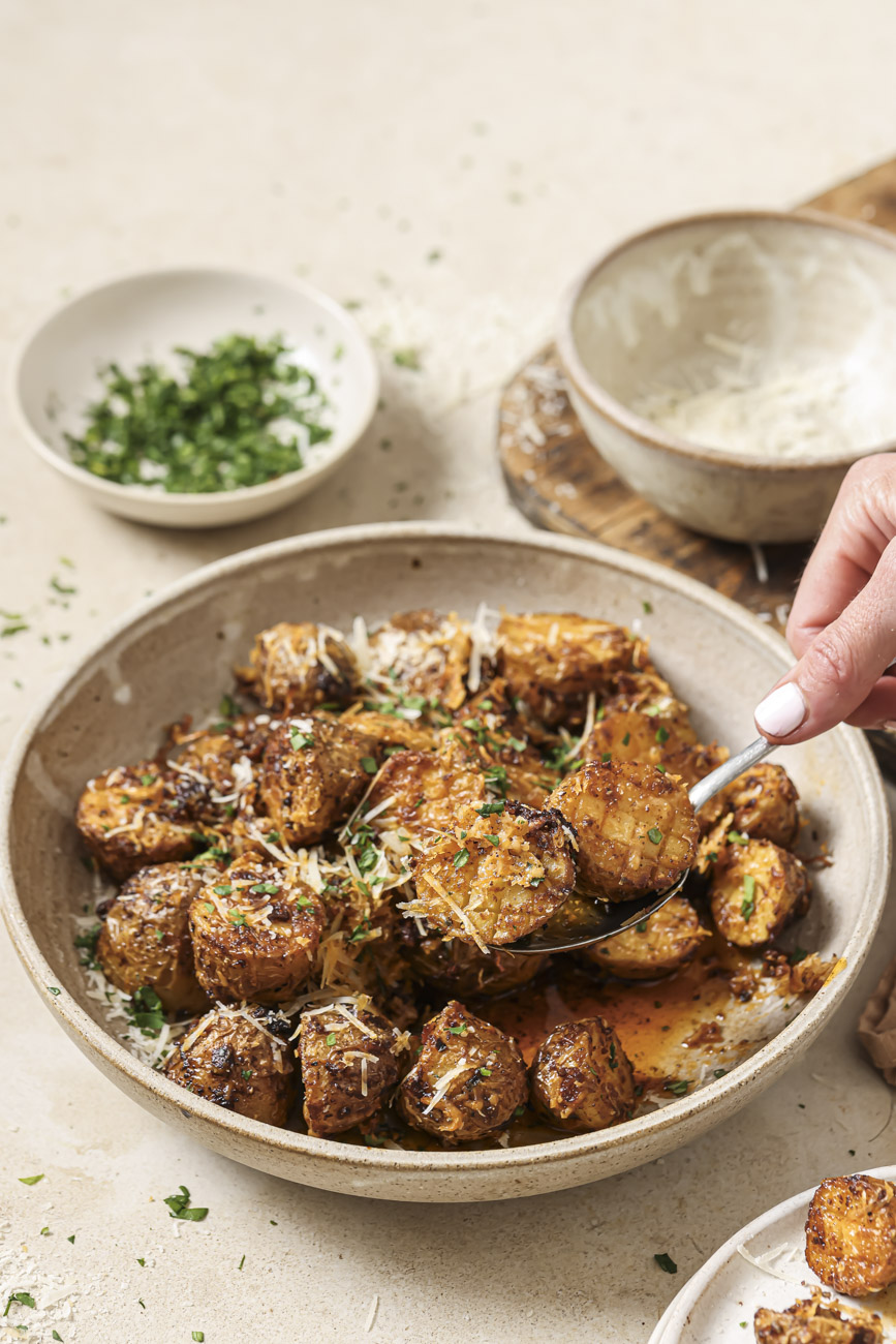 Spoon scooping up a bite of air fryer parmesan potatoes.