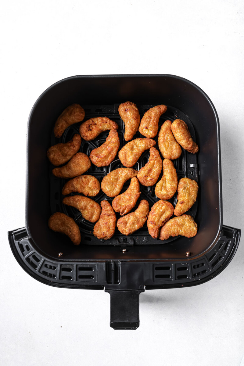 frozen chicken tenders in a black air fryer basket