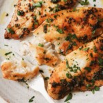 air fryer tilapia on a white plate with a bite taken out of it