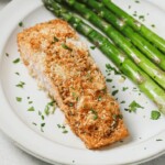 A close up of panko crusted salmon on a plate with asparagus.