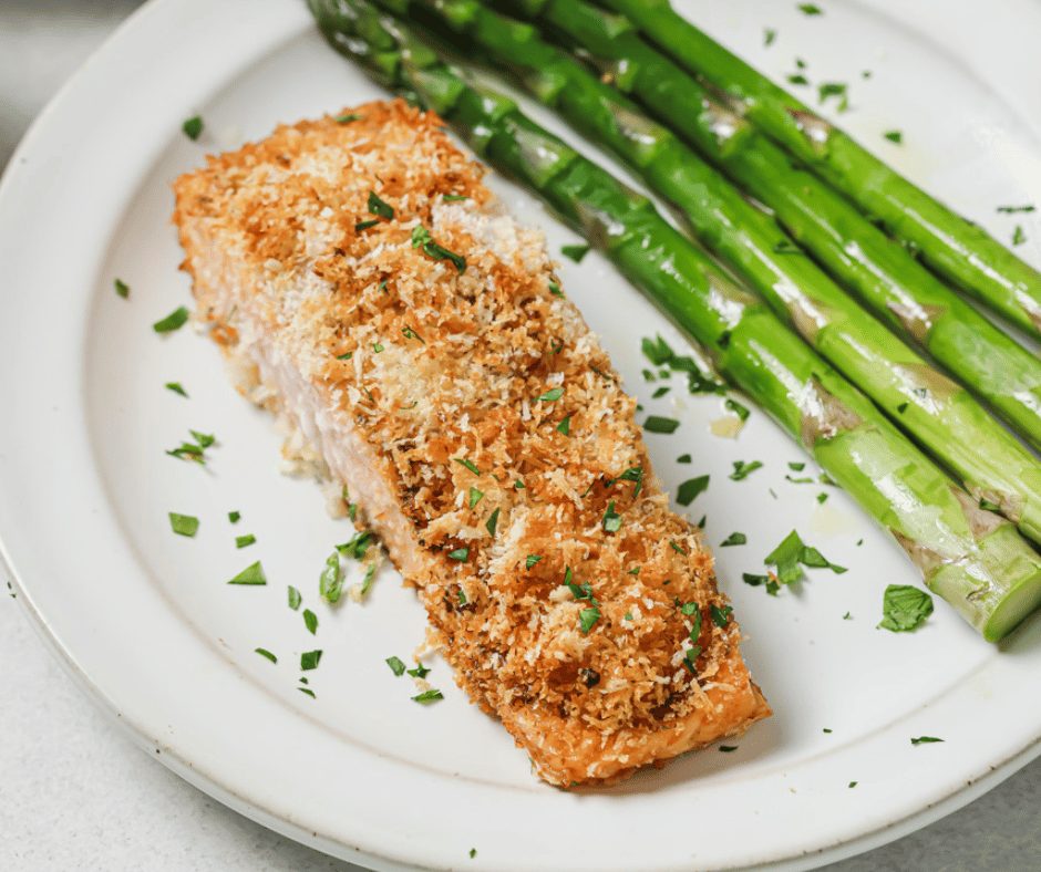 A close up of panko crusted salmon on a plate with asparagus.