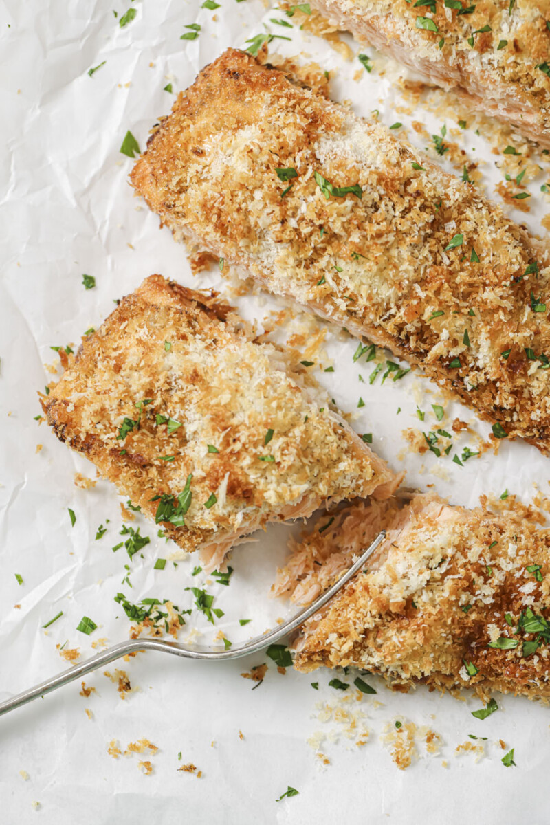 cooked salmon filets on parchment paper, one sliced in half with a fork