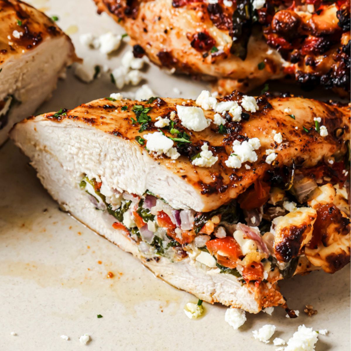 a close up photo of air fryer stuffed chicken breast sliced in half with feta cheese on top.