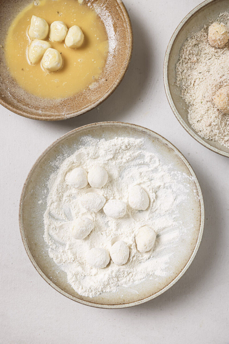 Coating mozzarella balls in breading.