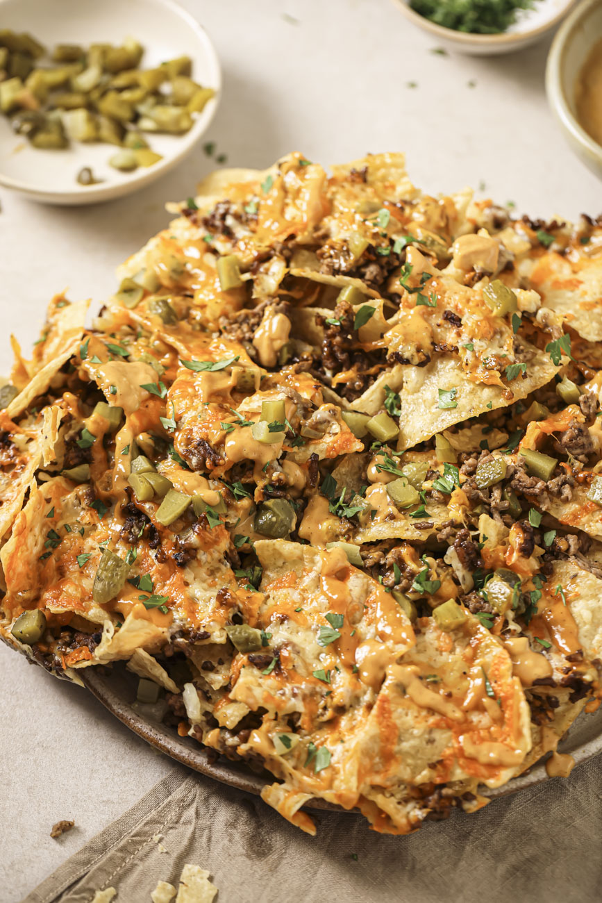 A plate of air fried nachos with burger sauce and jalapenos.