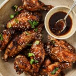 Close up of a dish full of air fryer asian wings and extra sauce.