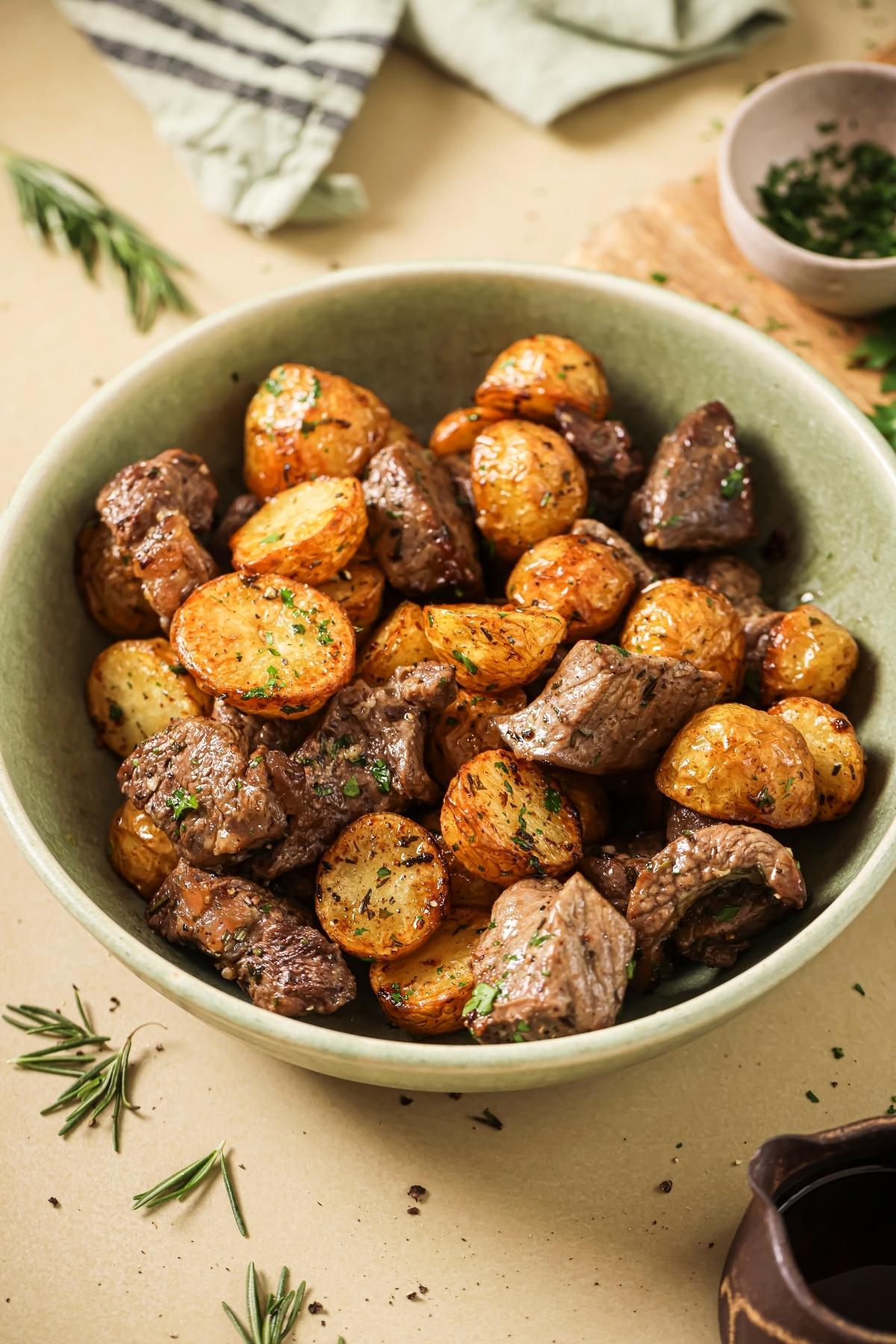 A green ceramic bowl full of air fryer steak bites.