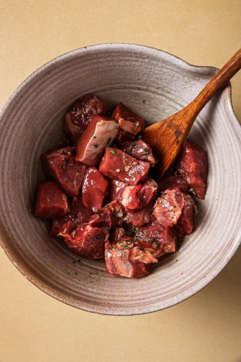 Tossing steak tips with oil and herbs.