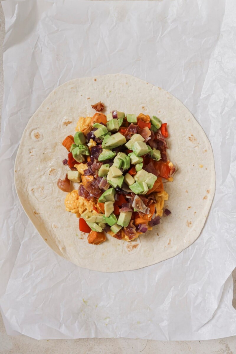 Arranging all air fryer breakfast burrito ingredients on a tortilla.