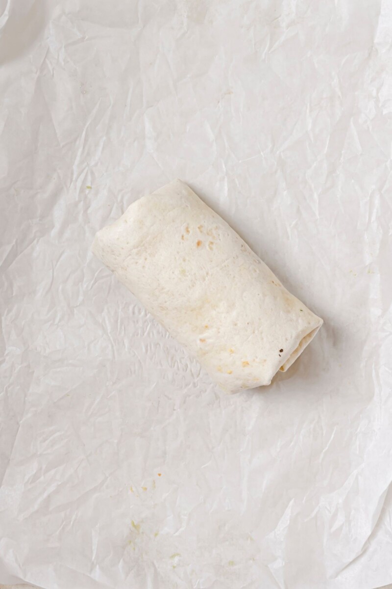 A fully wrapped and uncooked breakfast burrito.